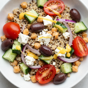 Mediterranean quinoa salad in a bowl with quinoa, chickpeas, fresh vegetables, and lemon dressing
