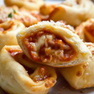 Easy homemade pizza rolls on a baking sheet golden brown and crispy served with marinara dipping sauce