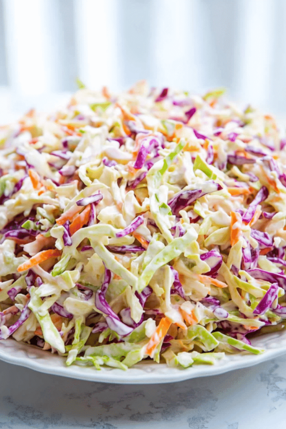 Easy creamy coleslaw in a white bowl with shredded cabbage carrots and fresh parsley