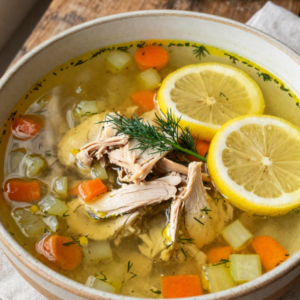 Mediterranean lemon chicken soup in a bowl with tender chicken, vegetables, and bright lemon-herb broth