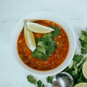 Bowl of crockpot chicken tortilla soup topped with crispy tortilla strips shredded cheese sour cream and avocado
