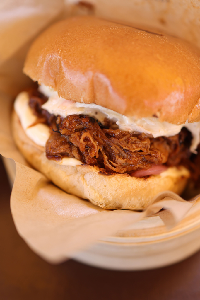 Apple cider pulled pork sandwich on a toasted bun with creamy slaw, wrapped in parchment paper